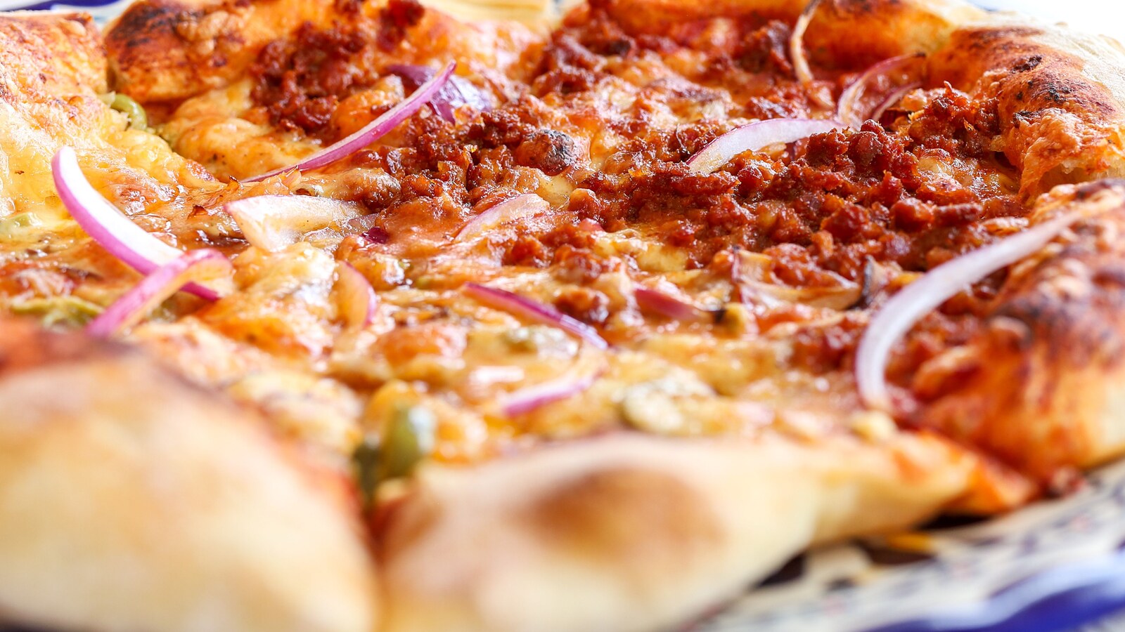 Close-up of pizza with cheese, red onion, and sauce