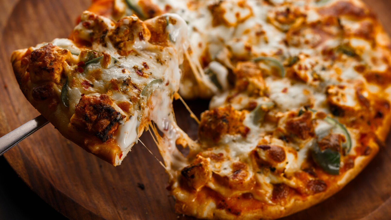 Pizza with a slice being lifted from a pie