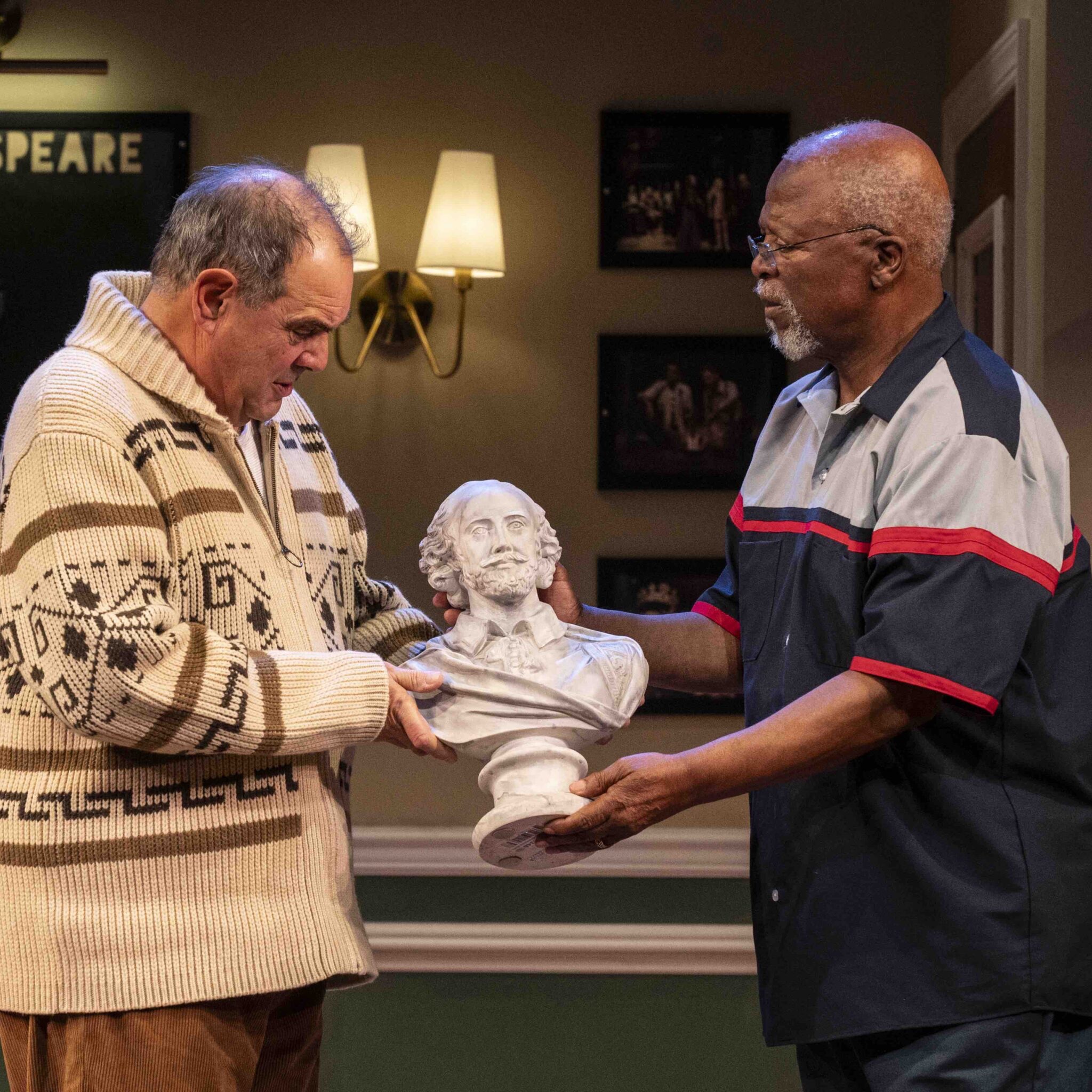 Two actors on stage holding a bust of Shakespeare