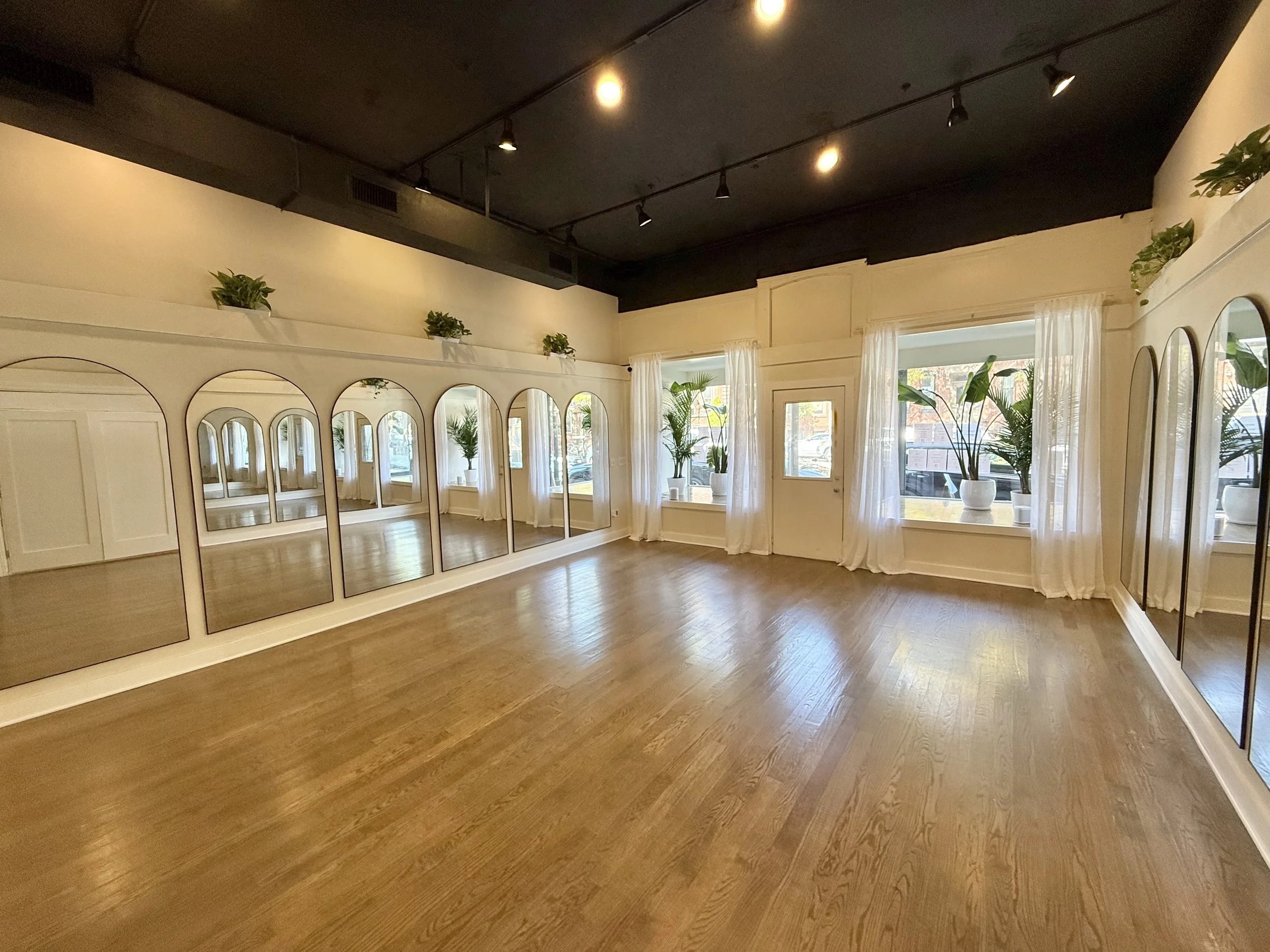 The studio at Luxe Leisure on East Broadway, with wood floors and a wall of arched mirrors.